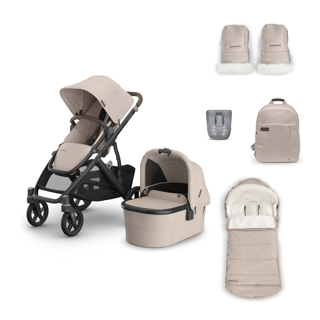 A multi-piece baby travel system set in a light beige/tan colorway, featuring a stroller, bassinet, footmuff, backpack, and accessories, arranged on a clean white background.