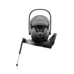 A grey and black infant car seat in a rotating base, shown from a side rotation angle on a clean white background.