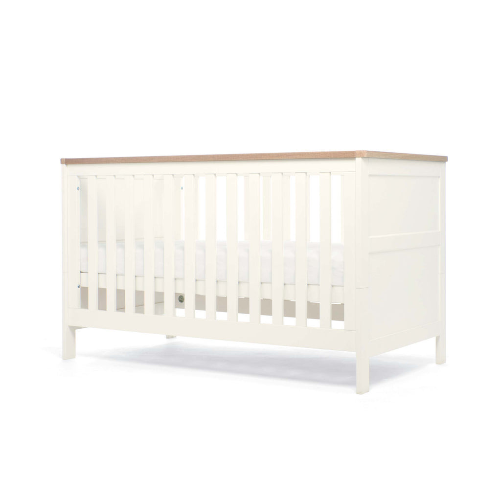 White cot bed with natural top showing second base height position on a white background