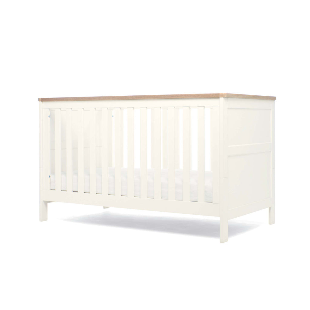 White cot bed with natural colour top showing lowest base height on a white background